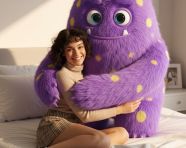 坐在一个毛茸茸的巨型可爱卡通怪物旁