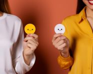 Female hands holding four colored smiley stickers isolated on ye