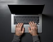 A hand in laptop typing in top view of computer with some on office desk, seo stock images for marketing campaigns