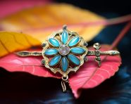 An indian rakhi atop a yellow leaf with blue and green flowers