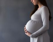 A woman is holding a pregnant belly on a gray background, pregnant women pictures, maternity photos