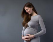 Pregnant woman caressing her belly on gray background, pregnant women pictures, maternity photos