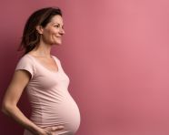 A pregnant woman against a pink backdrop, pregnant women pictures, maternity photos