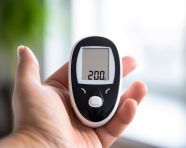 A close-up of a persons hand holding a glucose meter, diabetes concept