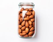 Clear glass jar of almonds on white background, almond image