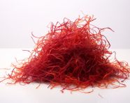 A pile of red saffron seeds is on the white surface, saffron flower image