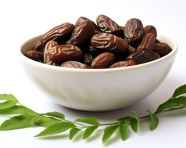 Dates in a bowl with green leaves isolated on white, sweet dates image