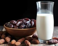 A glass of milk next to some dates, sweet dates image