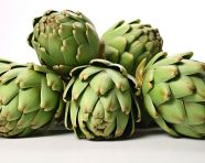 Several green artichokes on a white surface, artichoke image