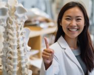 An asian doctor is showing her thumbs up, human bone image