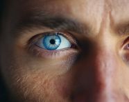 A man with a blue eye and a beard, men eyes close up image