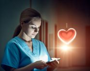 Nurse in scrubs using tablet to track patient's vitals, medical images stock