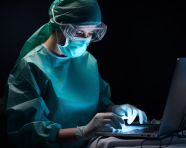 Female surgeon in mask and gloves standing on her laptop, medical images stock