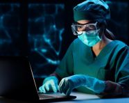 Surgeon in mask and gloves using laptop, medical images stock