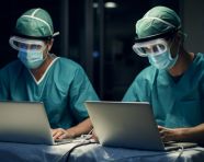 A pair of medical workers wear medical face masks over their laptops, medical images stock