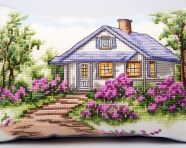 A cross stitch pillow with a countryside house and green flowers, cross stitching style art