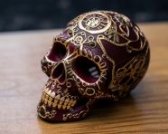 An intricately embossed sugar skull on a light wooden table, cross stitching style art