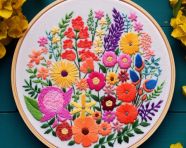 A colorful embroidery hoop full of beautiful flowers, cross stitching style art