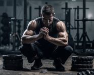 Man squatting with weights in black and white
