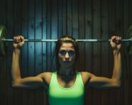 A young woman with a barbell lifting up
