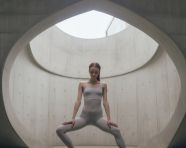 Woman doing yoga pose in front of concrete