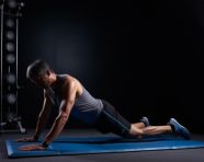 Man doing an exercise on his mat against a dark back background