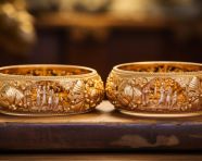 Golden bangles arranged on wooden surface