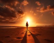 A silhouette of a person walking on a beach at sunset