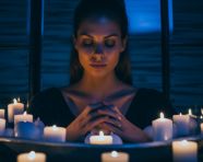 A person is sitting in a bathtub surrounded by candles
