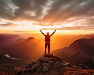 A person stands on a mountaintop looking out