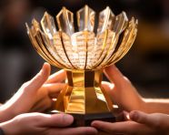 A persons hands are clasped together and they are holding a trophy
