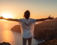 A man standing on a cliff overlooking the ocean