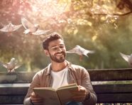 A young man is sitting on a bench in a park