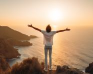 Man on cliff contemplates ocean